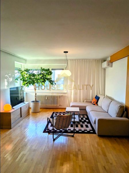 Living room in a 4-room apartment with a corner sofa and a floor with a wooden decor.