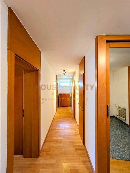 A hallway with a light wall and a floor with a wooden decor in a 4-room apartment.