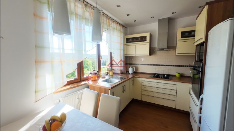 A kitchen in a 2-room apartment with a wooden decor floor and light curtains.