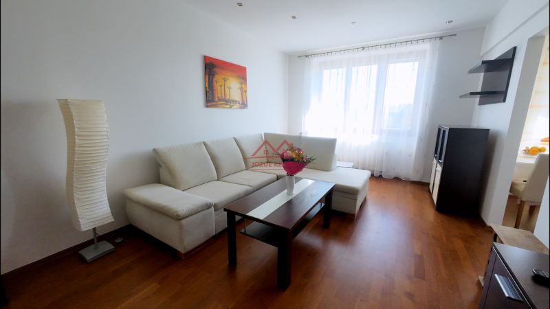 Living room with wood-patterned flooring, light-colored sofa, and wall painting in a two-room apartment.