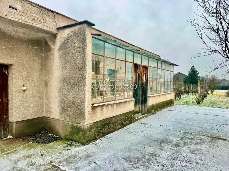 A family house in Dvorníky with a glass-enclosed veranda and a concrete walkway.