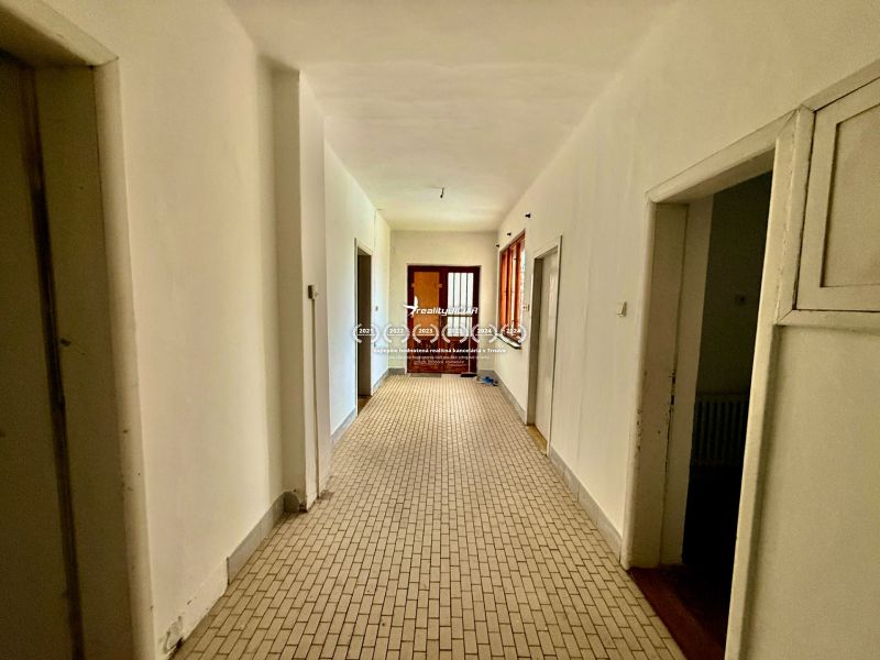 A hallway in a family house with white walls and neutral-colored tiles.