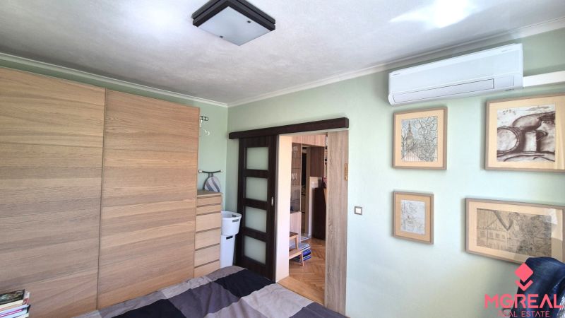 A bedroom with sliding doors, air conditioning, and a wardrobe in a 2-room apartment.