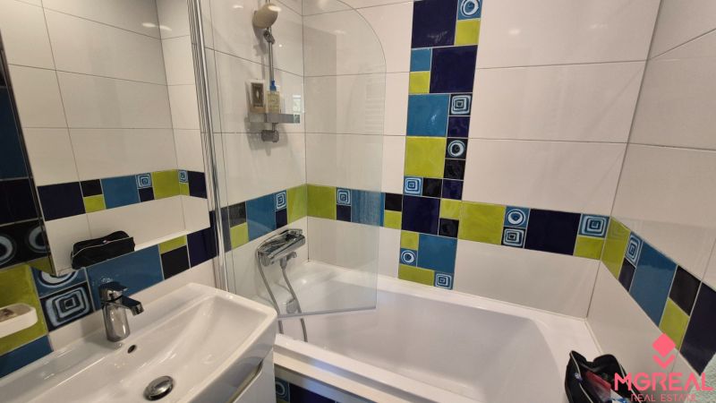 Colorful tiles in the bathroom with a bathtub in a 2-room apartment.