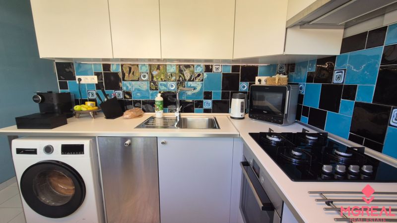 A kitchen in a 2-room apartment with tiles in a blue-black color combination.
