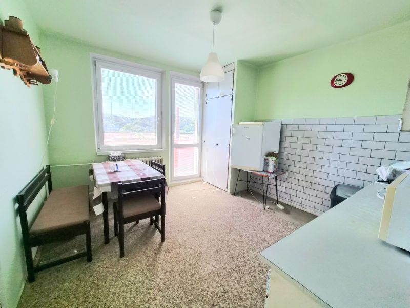 A kitchen in a 3-room apartment with a dining table, green walls, and a tiled wall.