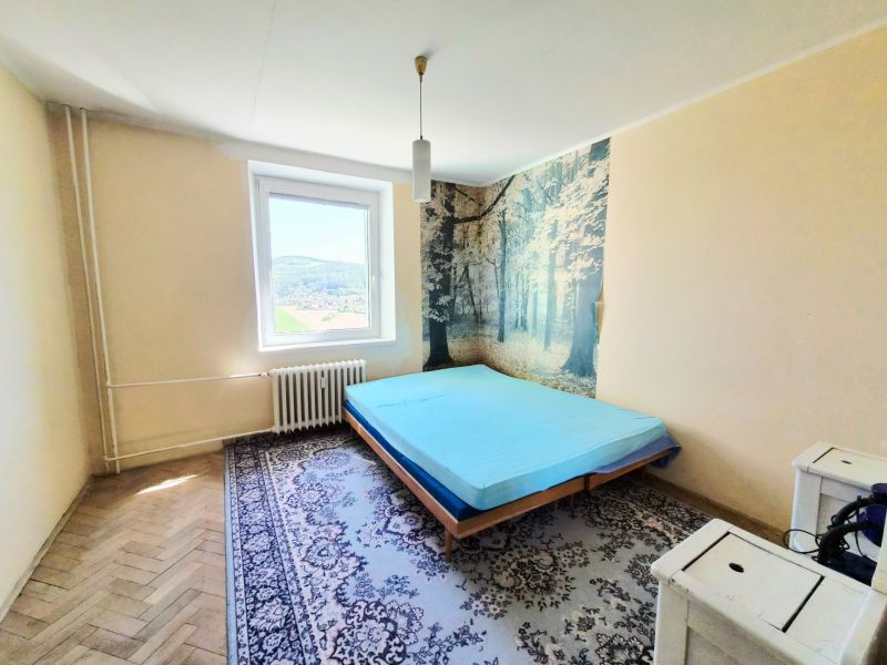 Bedroom with a bed, carpet, forest-themed wallpaper in a 3-room apartment.