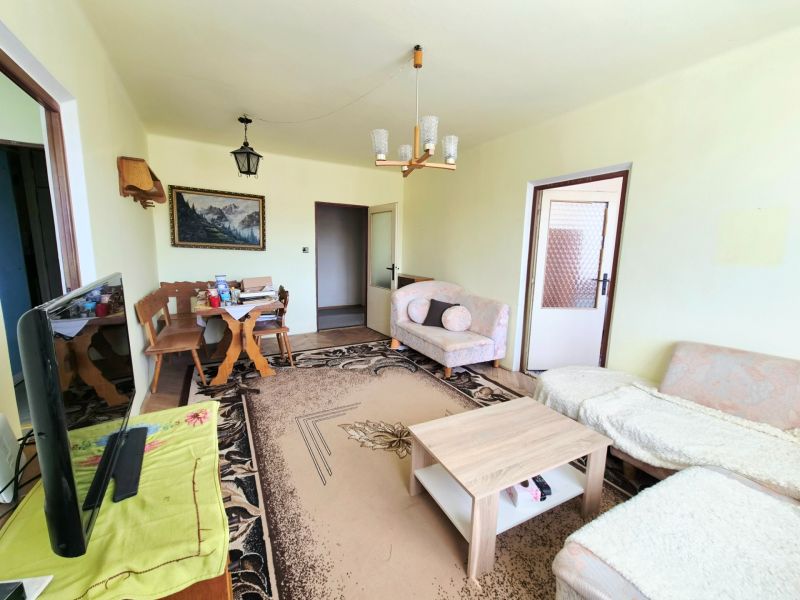 Living room with a sofa, table, and television in a three-room apartment.