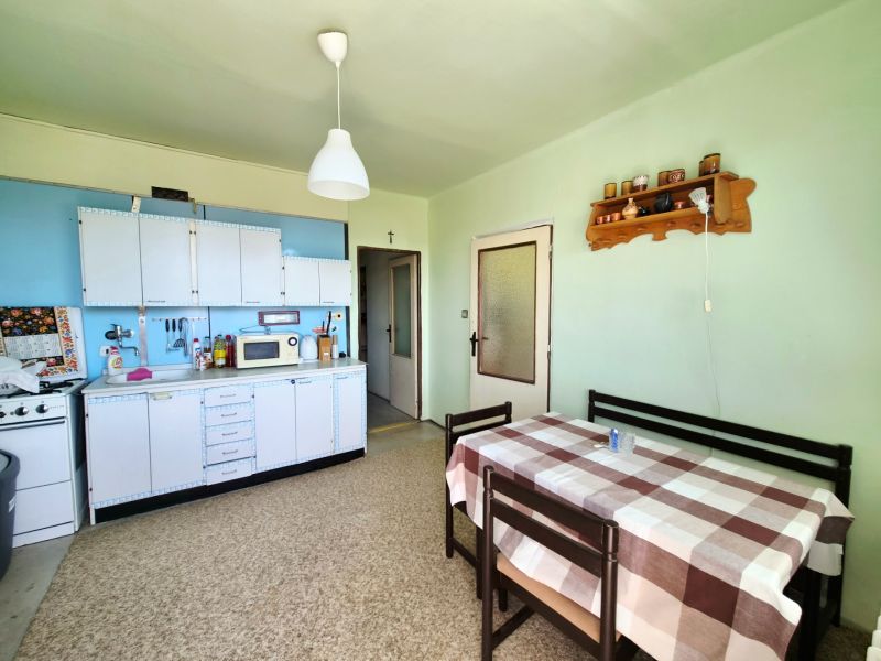A kitchen with a dining area, white cabinets, and a microwave in a 3-room apartment.