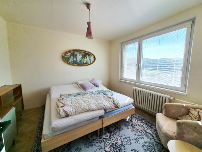 A bedroom with a bed, a chair, and a decorative painting in a 3-room apartment.