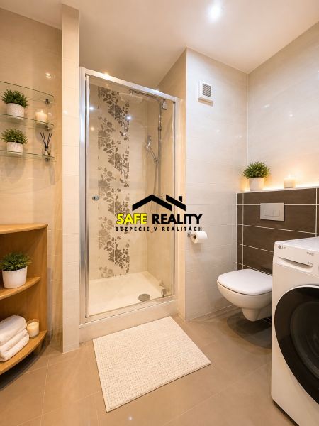 A bathroom in a 3-room apartment with a glass shower, a washing machine, and decoration.