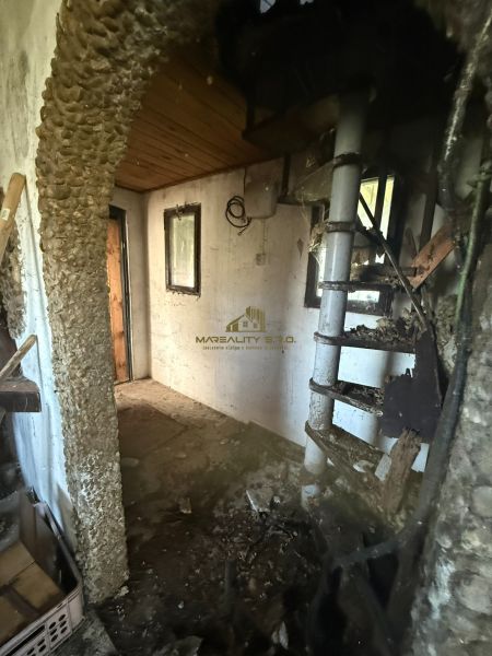 Internal staircase in a cabin with a stone wall and wooden ceiling.