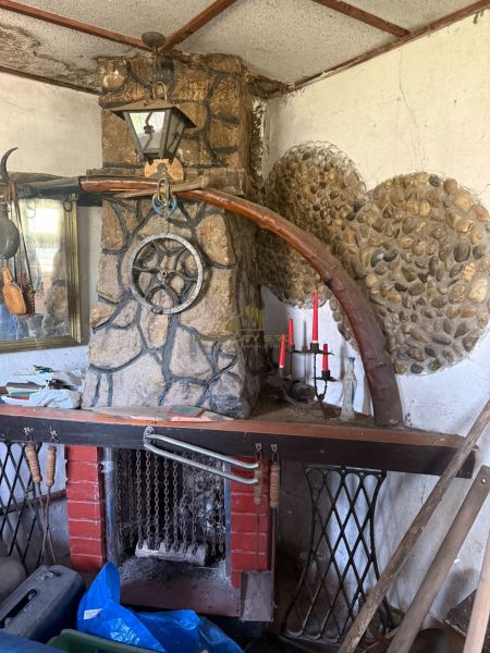 A fireplace in a cottage with rustic stone decor and a wall sconce.