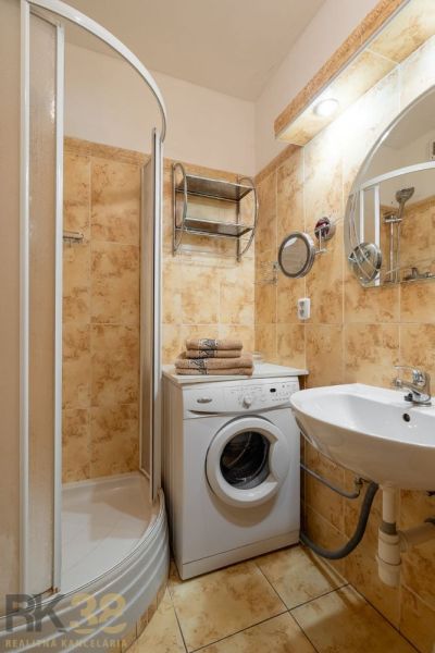 Bathroom with shower, washing machine, and sink in a 4-room apartment.