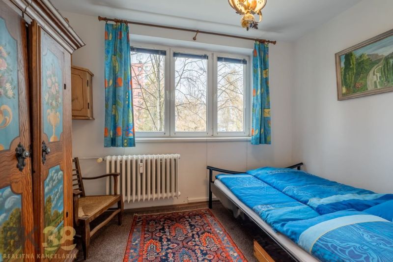 A room in a 4-room apartment with a blue bed and a colorful carpet, bright interior.