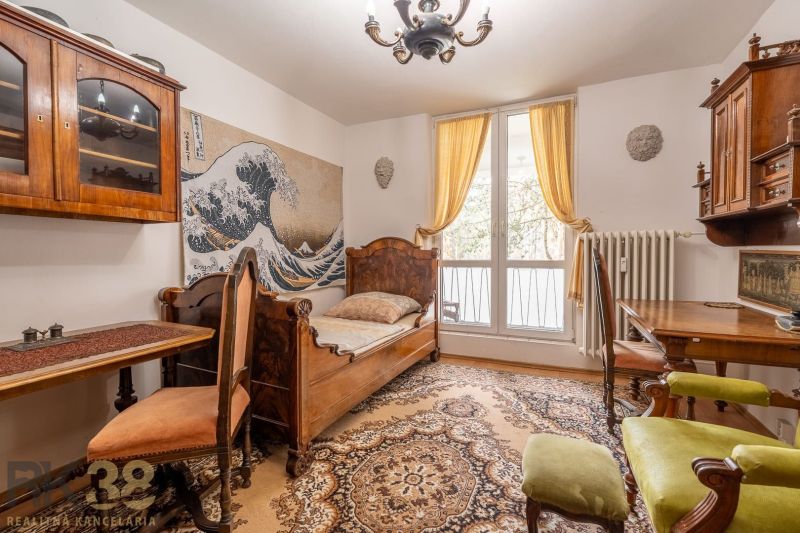 A room in a 4-room apartment with wooden furniture, woven wool, and a large window.