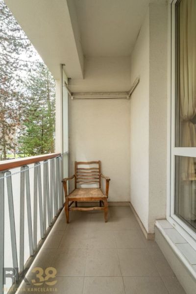 Balcony with a wooden chair and railing in a 4-room apartment.