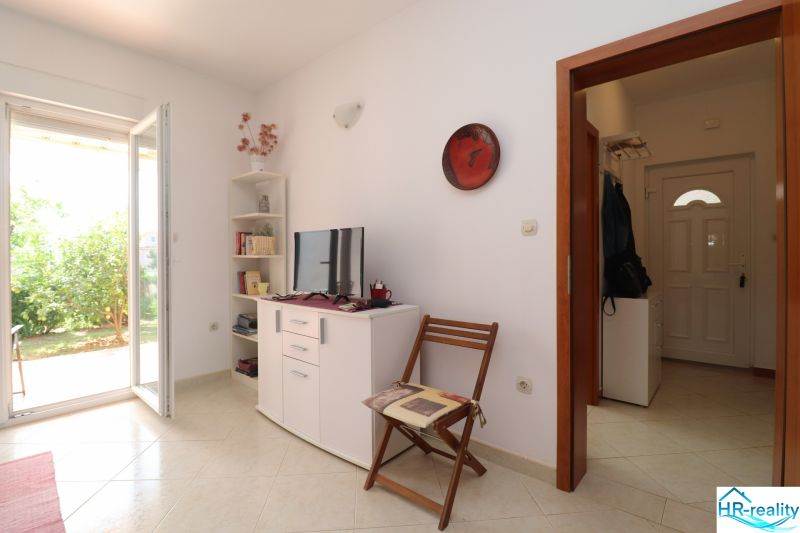 The interior of a family house with white furniture, a television, and open doors to the garden.