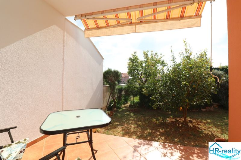 Terrace of a family house in Vodice with a table, chair, and a view of the garden.