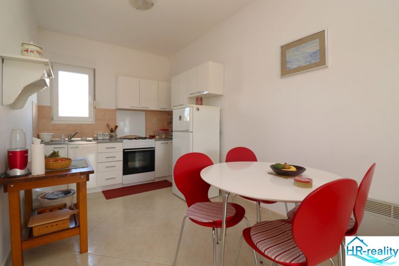 A kitchen in a family house with white furniture and red chairs.