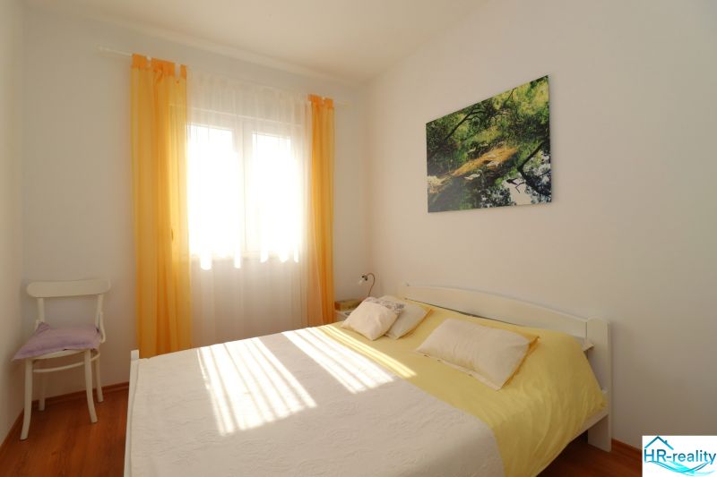 Bedroom in a family house with a bed, chair, and wooden decor flooring.