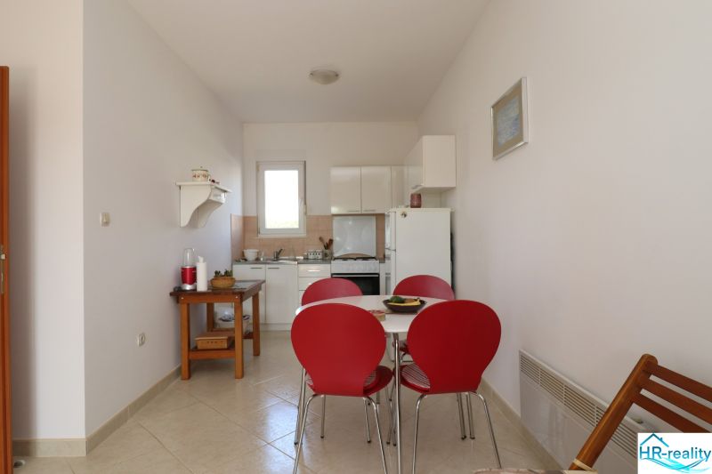 A dining room with red chairs and a white kitchen in a family house.