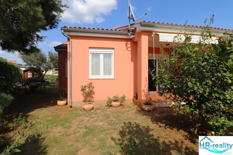 A family house in Vodice with a terracotta roof, surrounding greenery, and flower pots in the garden.