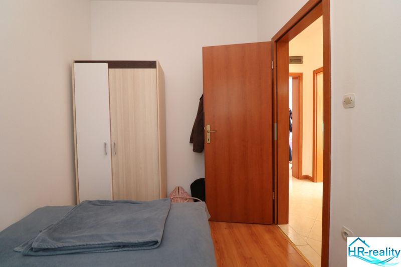 Bedroom in a family house with a bed, wardrobe, and wooden decor flooring.