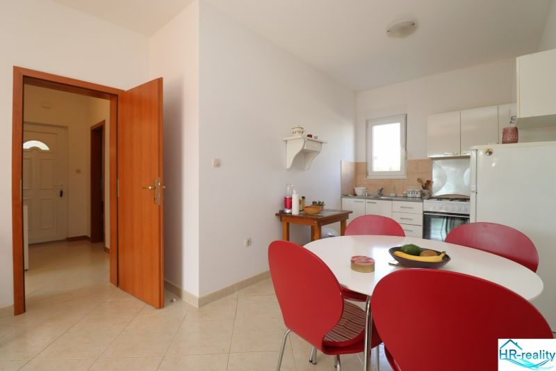 Dining room with a table and red chairs in a family house, light tiles.