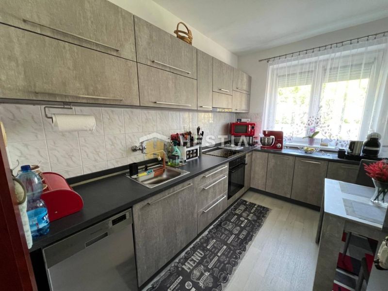 A kitchen in a 3-room apartment with appliances and a wooden decor floor.