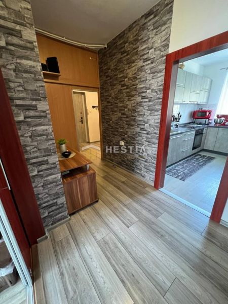 A hallway of a 3-room apartment with a wooden decor floor and stone-clad walls.