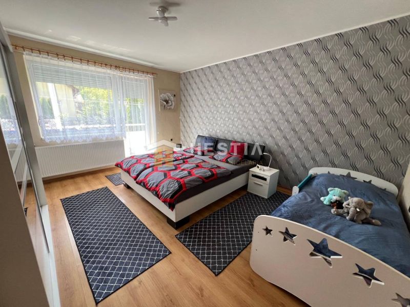Bedroom with a double bed, a child's bed, and a wooden decor floor in a three-room apartment.