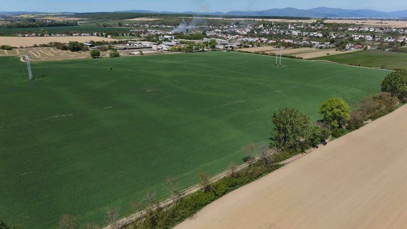 Vast green fields and Trhovište in the background, recreational plots in the surroundings.