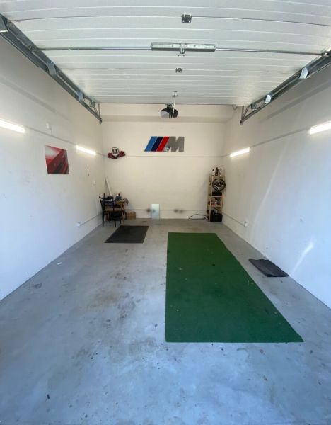 In the garages, there is a green carpet, a shelf, and a decoration with a logo on the wall.