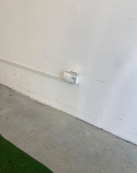 White wall with a socket and concrete floor in the garages on Kazanská Street.