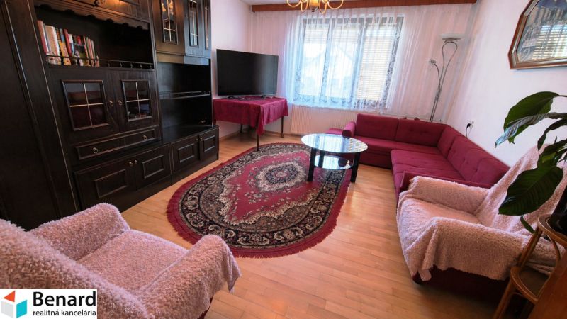 Living room with dark furniture, wood-patterned floor, red sofa set, and carpet.
