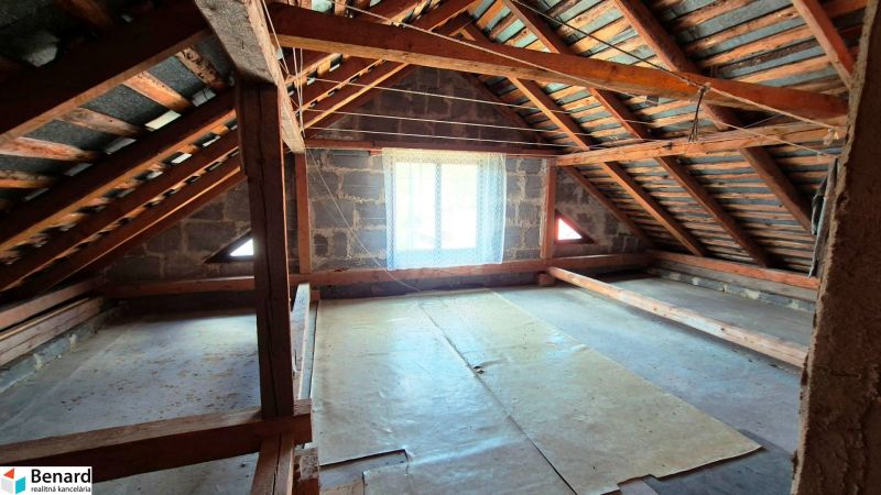 An attic with wooden beams in a family house, illuminated by a window.