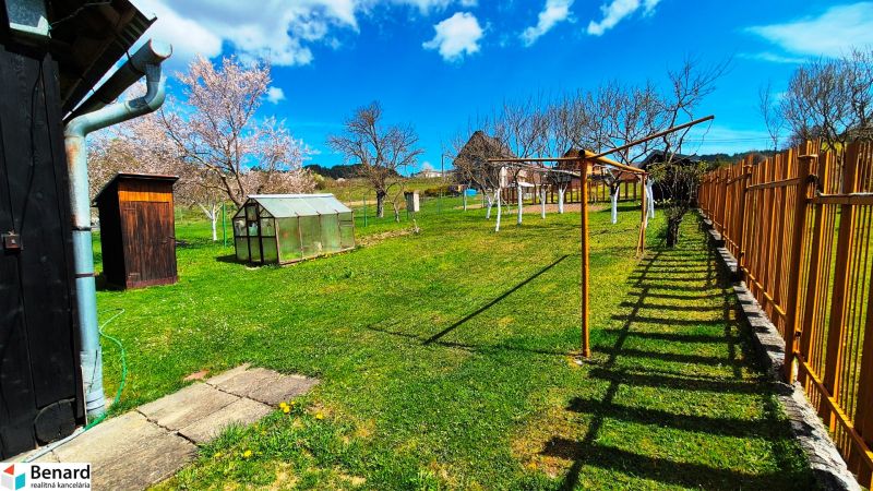 The garden of a family house in Jarabina with a wooden fence and a greenhouse.