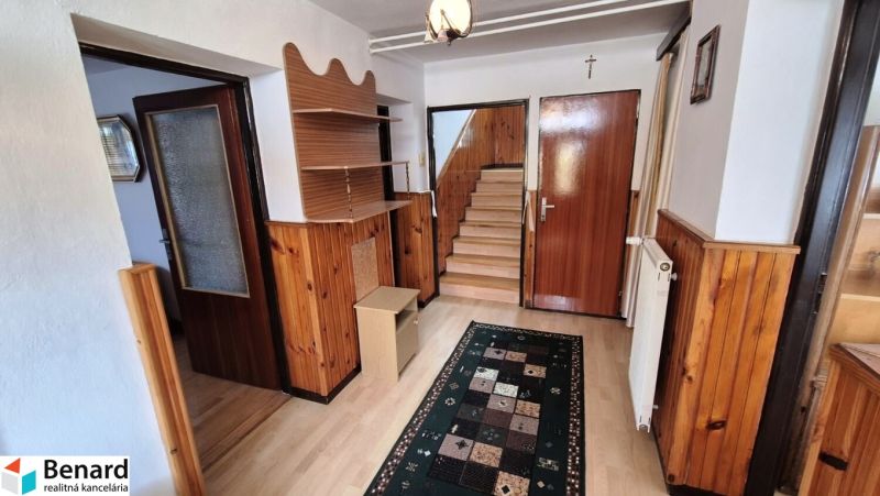 Interior with wooden paneling, floor with wooden decor, stairs, carpet, and furniture.