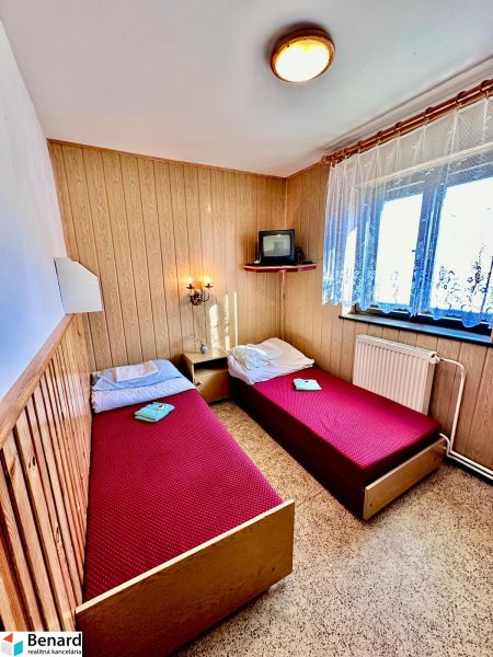 Wooden paneling with two beds, a television, and a window in a family house.