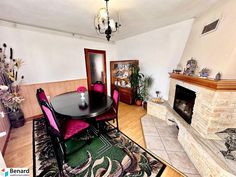 A dining room in a family house with a fireplace, furniture, and flooring with a wood decor.