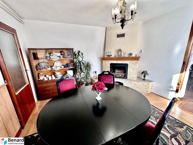 Dining room in a family house with a fireplace, black table, and a dish cabinet.