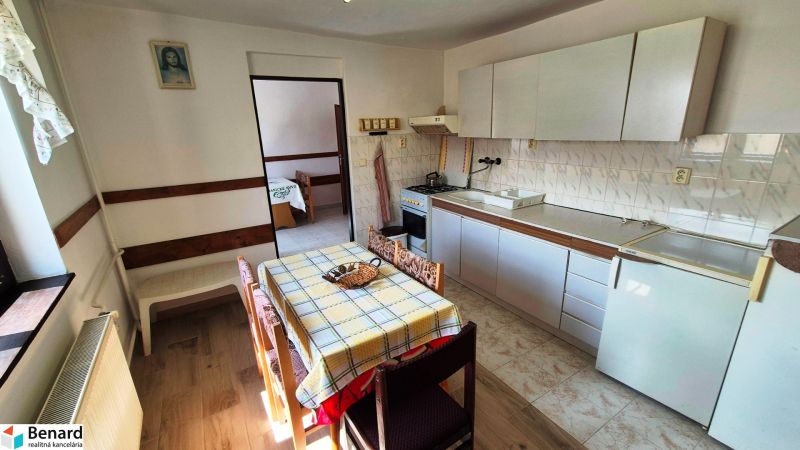 A kitchen in a family house with a dining table and a wooden decor floor.