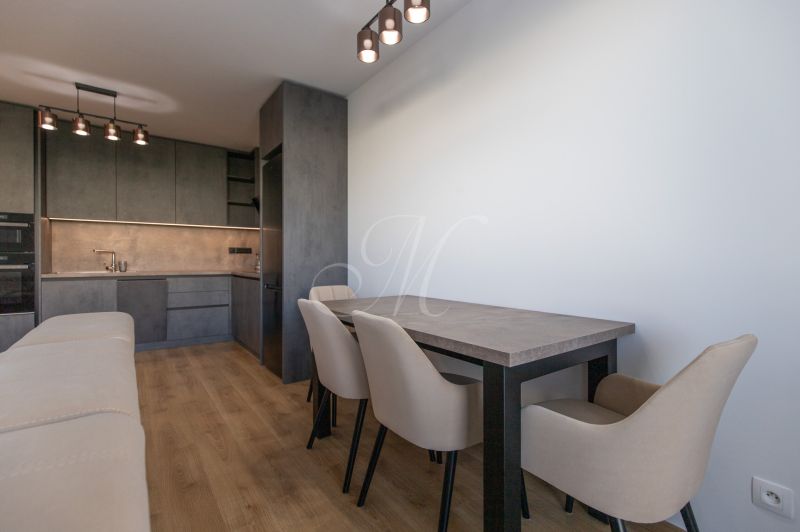 A kitchen in a 2-room apartment with cabinets, a table, and a wooden decor floor.