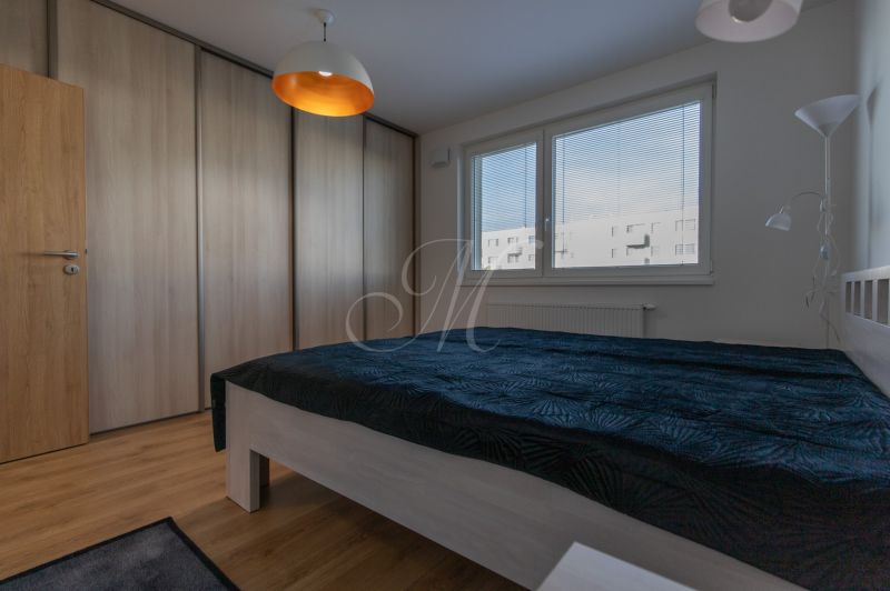 Bedroom in a 2-room apartment with a bed, built-in wardrobe, and wooden decor flooring.