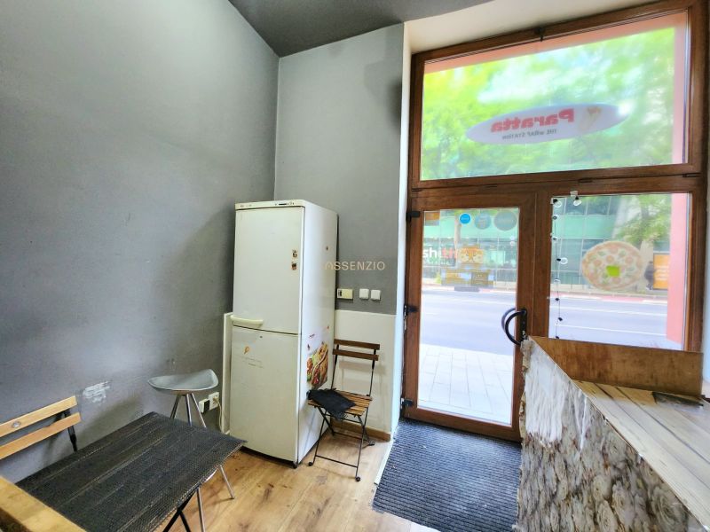 Gastro premises with a wooden decor floor, a refrigerator by the table, and entrance doors.
