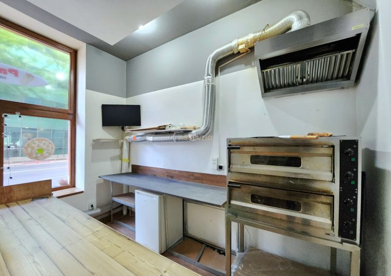 A bakery oven and a table with a hood in a gastro space on a floor with a wooden decor.