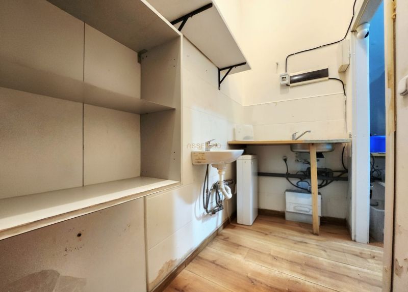 A kitchenette in gastro premises with shelves, a sink, and a floor with a wooden decor.