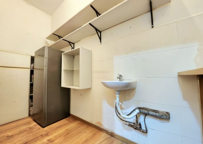 Gastro premises with a refrigerator, sink, shelves, and a floor with a wooden decor.