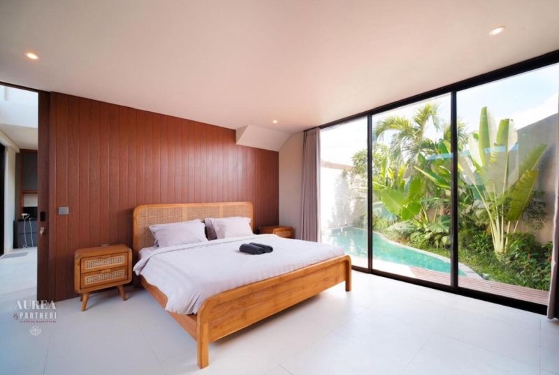 Bedroom in a villa with a pool, wooden decor flooring, tropical garden.